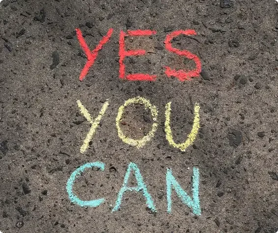 A motivational photo of the words 'YES YOU CAN' written in bright red, yellow, and blue chalk on asphalt, symbolizing the positive encouragement and potential for change offered in counseling.