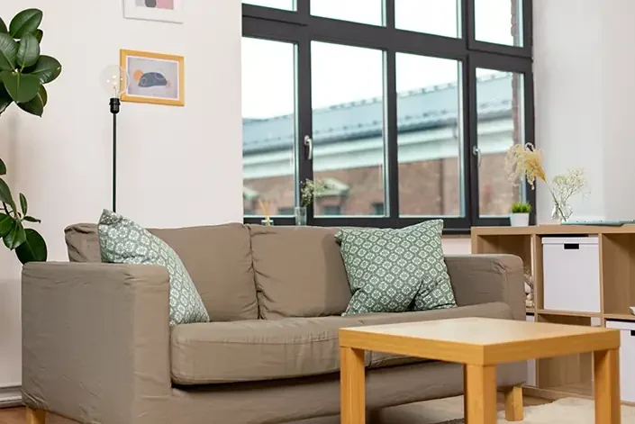 A cozy counseling office with a comfortable sofa, a small table, and a large window letting in natural light, creating a welcoming atmosphere.