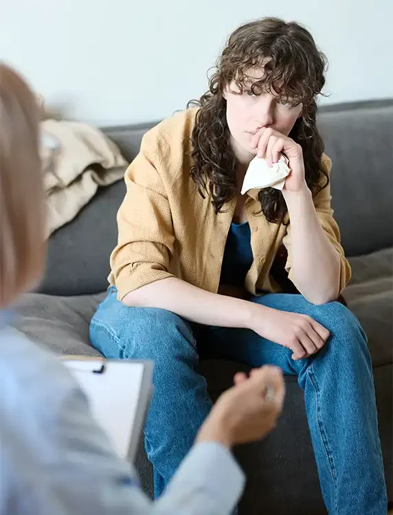 Young woman holding a tissue while processing difficult emotions during a professional counseling session.