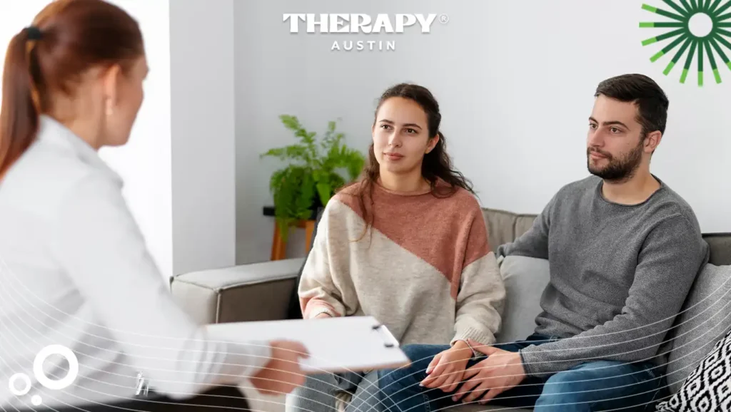 Therapy Austin counselor handing a clipboard to a couple seated on a couch during a counseling session.